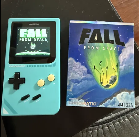 Customer's turquoise ModRetro Chromatic showing the Fall from Space title screen beside the game's illustrated box.